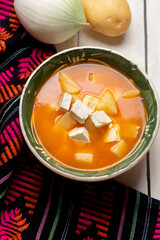 Mexican potato soup with panela cheese on white background