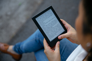 young latin woman reading an ebook on digital tablet device. Focus on the ebook.