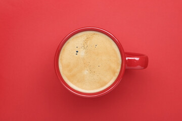 Cup of aromatic coffee on red background, top view