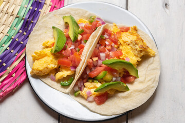 Breakfast egg tacos with flour tortilla and fresh sauce on white background