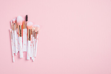 Set of makeup brushes on pink background. Flat lay, top view, copy space.