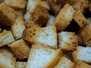 Selective focus on slices of fried white bread close-up. Tasty rosy croutons. Abstract food background.