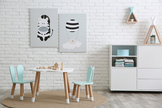 Cute children's room interior with little table near white brick wall