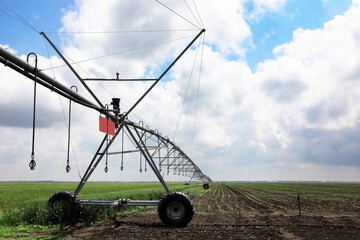 Modern irrigation system in field under cloudy sky. Agricultural equipment