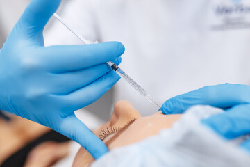 Injection into the forehead without a face. Only the hand and the injection are visible