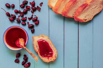 Dried rosehips, rosehip marmalade and jam spread on a bread slice. Top view. Copy space for text.
