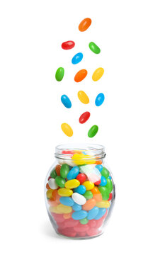 Delicious color jelly beans falling into jar on white background