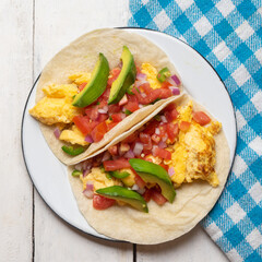 Breakfast egg tacos with flour tortilla and fresh sauce on white background
