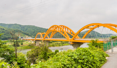 Fototapeta premium Yellow arched bridge over river