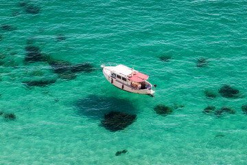 Amazing view of the crystal clear azure water of the sea and the yacht. The view from the top. Summer vacation at the sea. Fishing and yacht holidays.