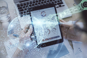 Double exposure of man's hand holding and using a digital device and data theme hologram drawing....