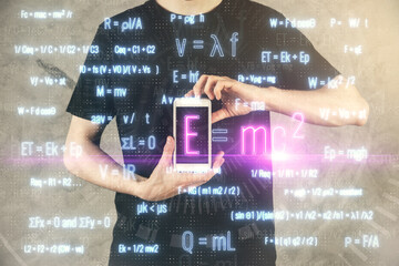 Double exposure of man's hands holding and using a phone and formulas drawing. Education concept.