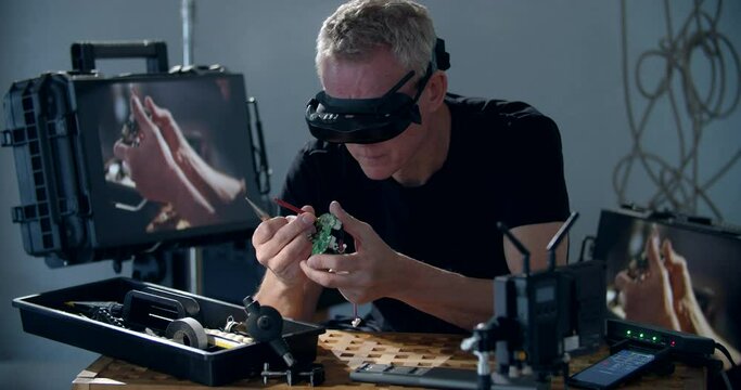 4K: Male Engineer Soldering a Circuit Board In his laboratory.  Fantastic dramatic picture with several screens, lots of technologies and smoke.