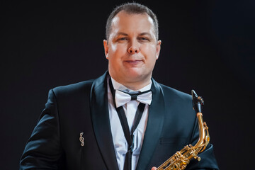 Naklejka premium Portrait of Tranquil Male Saxophonist Player Against Black