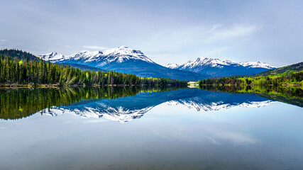Reflection of the Rocky Mountains range on the smooth water surface of Yellowhead Lake in Robson Provincial Park in British Columbia, Canada