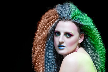 Creative Ideas. Caucasian Girl With Frizzy Colorful Hair and Artistic Eyes Makeup. Posing Against Black.