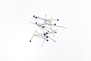 Pile of sewing pins on white background, top down.