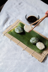 Hand use chopstick pinch Chinese Chive Dumpling, (Kanom Gui Chai)mixture of flour with Chives Garlic Cutlets Steamed Served Sweet Black Soy Sauce decorate with carved cucumber,spring onions vegetable.