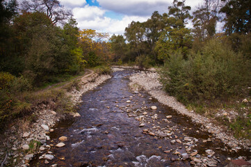 Fototapeta na wymiar A beautiful mountain river flows between the rocks and trees