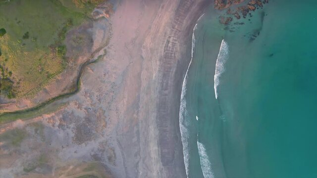 Aerial: Flying over beach and ocean waves looking down. Elliot bay, Northland, New Zealand