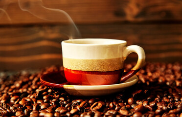 Cup with aromatic hot coffee on coffee beans closeup with blur.