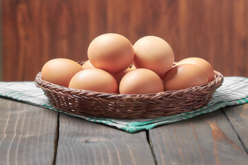 Chicken eggs in a wooden wicker basket on an old wooden dark table
