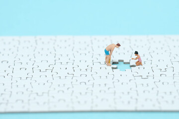 水色の背景にワンピース足りない白色のパズルの穴を除く男性の女の子のミニチュア人形