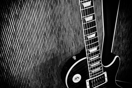 Image of an electric guitar leaning against an amplifier speaker cabinet - black and white gritty effect