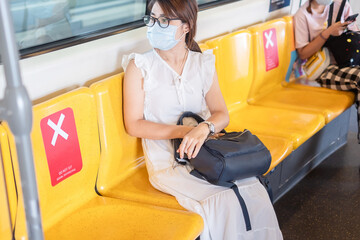 young Asian woman wearing Surgical face mask protect coronavirus inflection, tourist girl sitting...