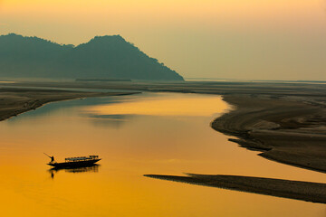 sunset on the river,silhouette of a man rowing a boat,Mayong, Brahmaputra river ,Assam,India - obrazy, fototapety, plakaty