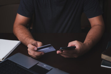 Men are paying credit cards. man makes the payment by credit card on the laptop and holding phone