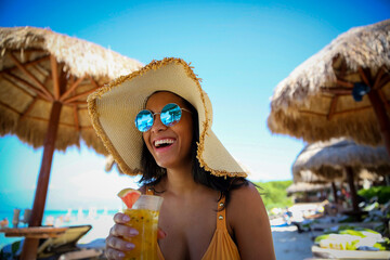 smiling woman on beach drinking a cocktail - obrazy, fototapety, plakaty