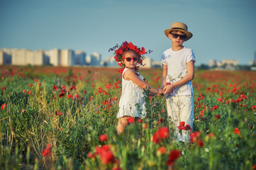 Portrait of a boy and girl in a field with poppies . Friends on an outdoor walk