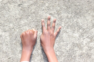 Hands with four fingers up and a closed fist over grey concrete background