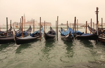 An array of boats parked during rainy day in the Venetian Lagoon enclosed bay of the Adriatic Sea.
