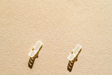 Aerial view of two sunbed, standing at distance from each other on sandy beach. Summer and travel concept. Minimalism