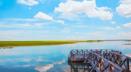 Old wooden pier in the lake on the background cloudy blue sky