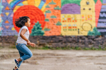 African american cute little girl having fun while run away, racing on the track in city street at summer. Grow up, speed, hurry, childhood, and people concept.