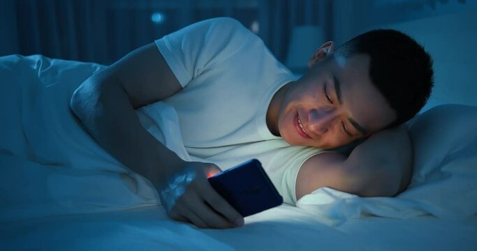 man use smartphone on bed