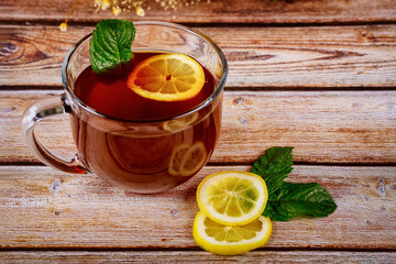 Cup of brewed black tea and lemon on wooden table.