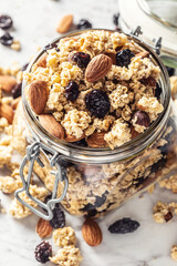 Jar of muesli with nuts, almonds grapes and dried fruits - closeup