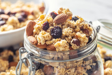 Jar of muesli with nuts, almonds grapes and dried fruits - closeup