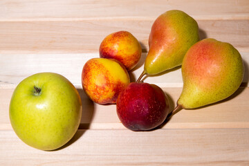 Red-yellow peaches, yellow pears, green apple lie on a wooden table close-up, fruit assorted