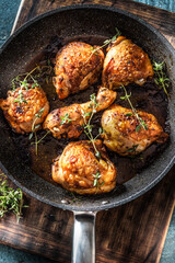 Tasty chicken legs roasted in ceramic pan with thyme - closeup