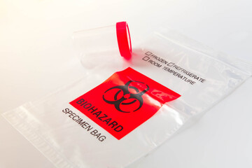 Biohazard bag with plastic bottle for sputum collection. Concept of lab test for diagnosis of coronavirus infection. Selective focus