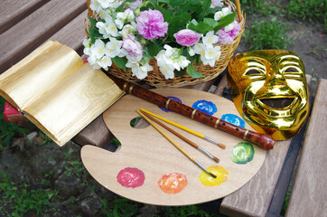 Attributes of the arts. Art palette, brushes, violin, bow, theater mask, open book, a bouquet of...