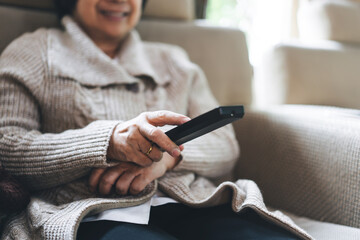 Asian elderly hand holding remote television and watching movie.