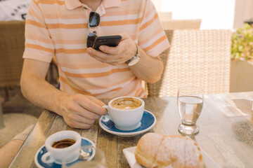 Close up of man taking photo of breakfast at cafe on sunny day.