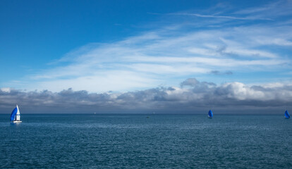 Fototapeta na wymiar three sailbotas sailing on the sea, in the background a beautiful cloudy sky