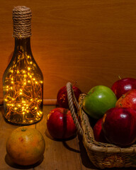 Bodegón, cesta de frutas con lámpara de botella.